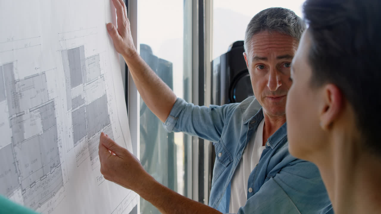 오피스 4k에서 블루프린트에 대해 논의하는 백인 사업가들의 측면 뷰