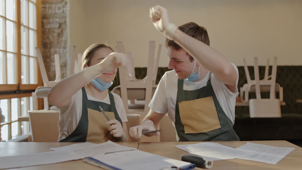 두 명의 직원, 한 남자와 한 여자, 식당의 주인이 테이블에 앉아서 수익을 세고, 청구서를 세고, 기하고, 미소 짓고, 좋은 결과를 봅니다.