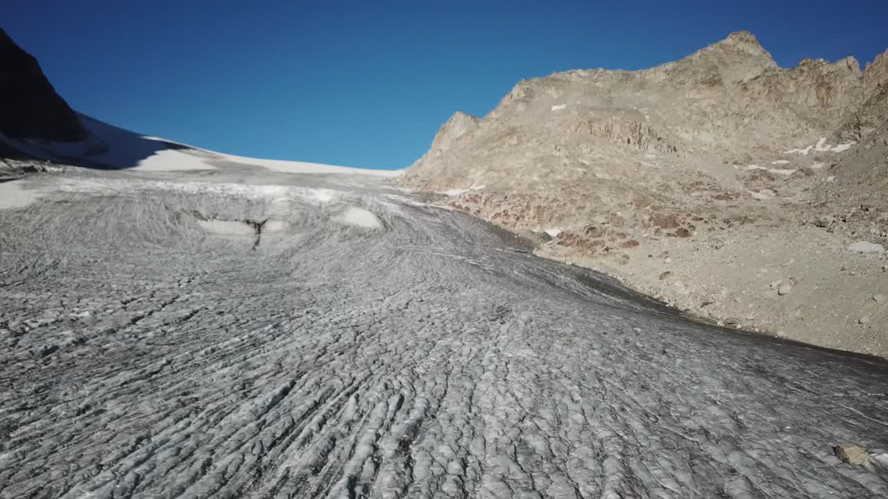 gran glaciar con crestas y grietas que crean una llanura en altas montañas rocosas suizas, disparo de drones