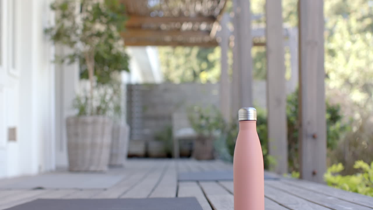 Pink water bottle on wooden deck in outdoor patio area with plants