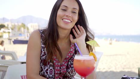 una mujer feliz y amigable bebiendo un cóctel tropical.