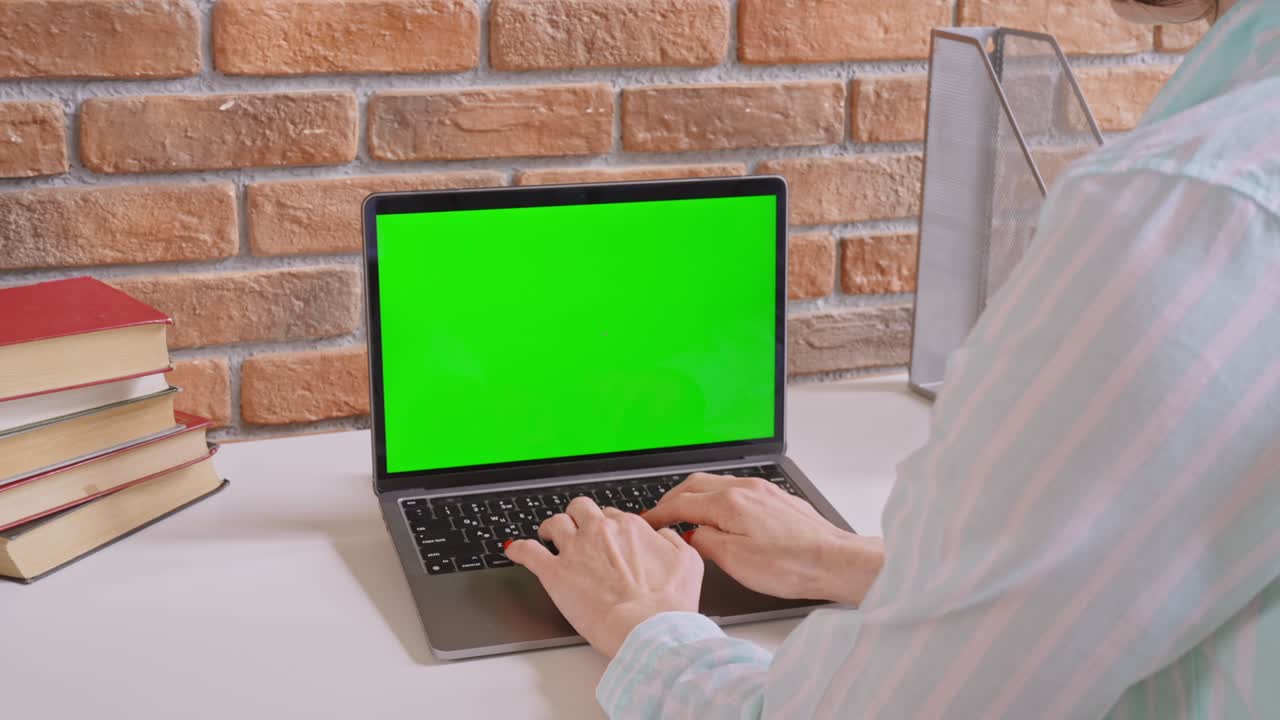 mujer irreconocible escribiendo en una computadora portátil con pantalla verde