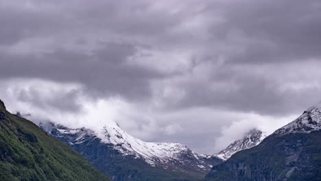 clouds over the snow-covered mountains. valldalen valley, norway