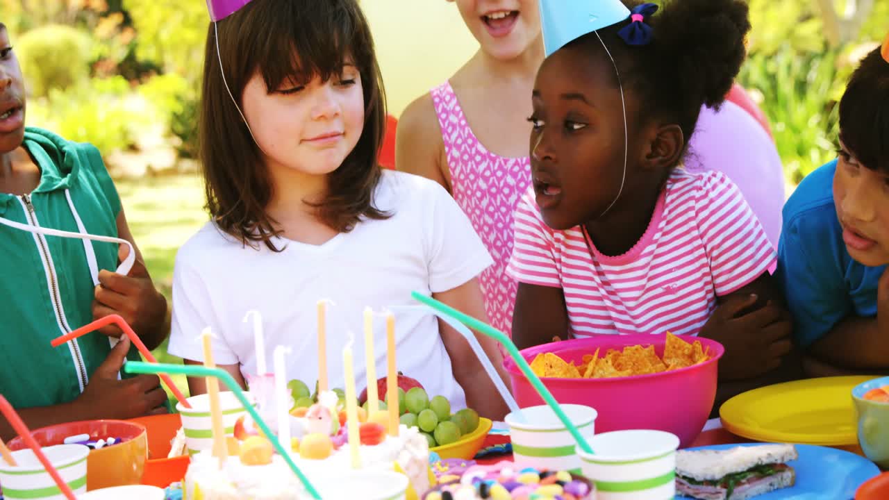 niños de pie cerca de la mesa con comida y celebrando un cumpleaños