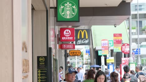 a street view of people walking past the american multinational companies starbucks coffee and mcdonald's stores in hong kong, china.