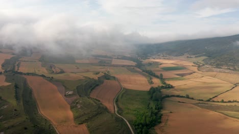 Agricultural-fields-near-mountains-under-blue-cloudy-sky