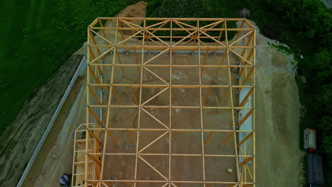 wooden-framework-on-construction-building-site,-building-a-house-process,-home-skeleton,-home-foundation,-Housing-gables-roof-on-wood-sticks,-home-under-construction,-aerial-overview,-drone-shot