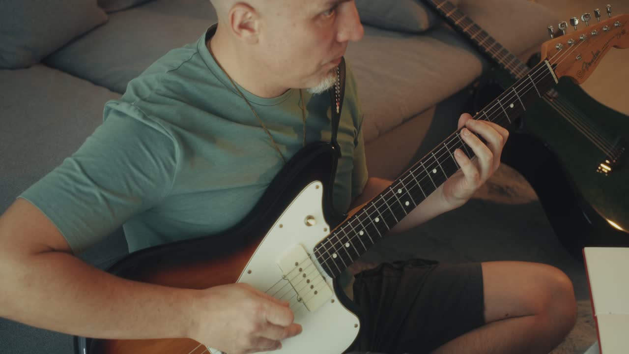 Uomo che suona la chitarra elettrica a casa