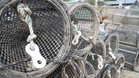 fishing harbour stacked lobster pots outside coastal marine waterfront dolly left