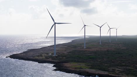 row of wind turbines spin on north volcanic rocky coast of tropical island