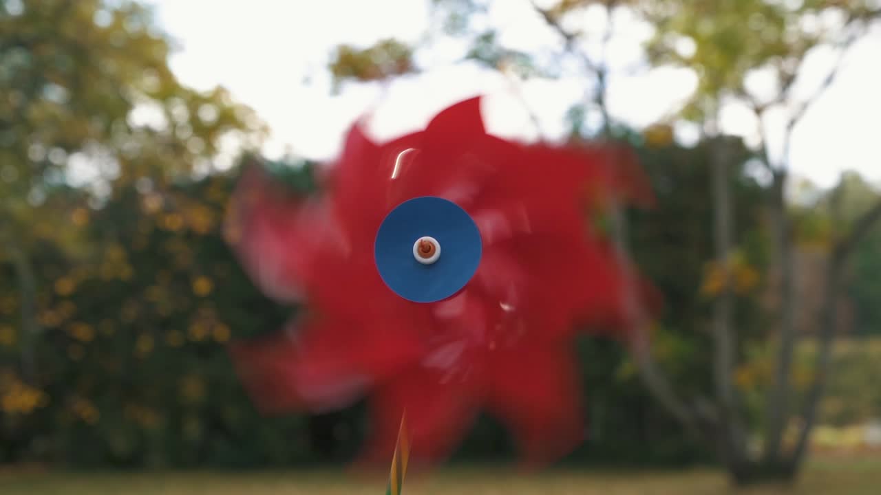 움직이는 풍향계의 화려한 장난감, 가을을 배경으로 느린 동작으로 풍차 장난감