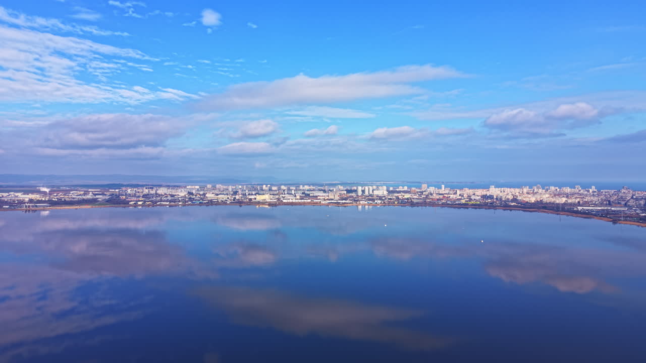 Sky and water meet above the city as clouds float over buildings in a late afternoon view of the landscape near the water's edge