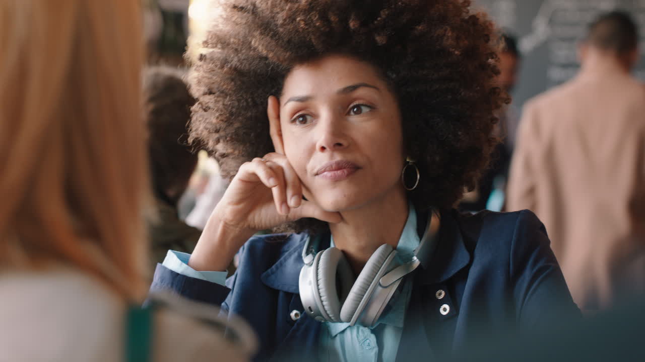 beautiful mixed race woman with afro hairstyle chatting with friend in cafe socializing enjoying conversation hanging out in busy coffee shop