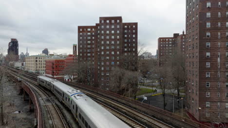 Aerial-view-low-over-a-train-in-Upper-Manhattan,-cloudy-evening-in-New-York,-USA