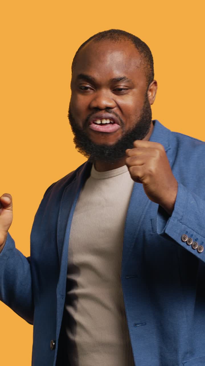 Vertical video Man dancing from happiness, celebrating achievement, studio background