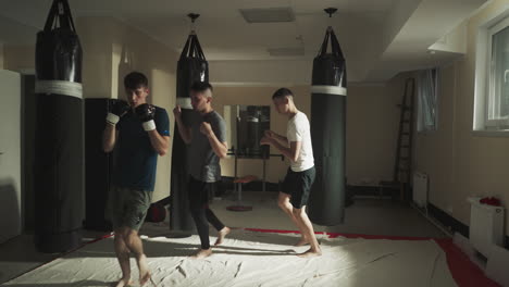 boxers run warming up hands in fighting gym. kick-boxers group exercises together on rink in martial arts club slow motion. combat sportsmen team