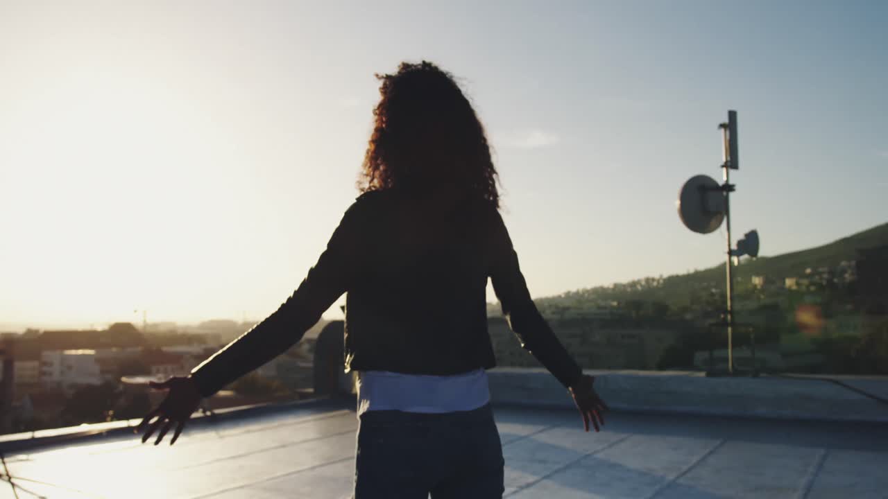 Jovem mulher estilosa em terraço urbano com os braços estendidos
