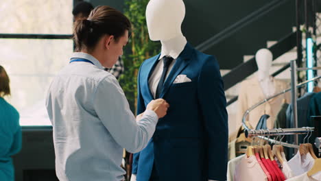 trabajador que arregla el maniquí con el traje