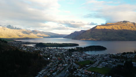 setting sun casts light on mountains next to queenstown, aerial