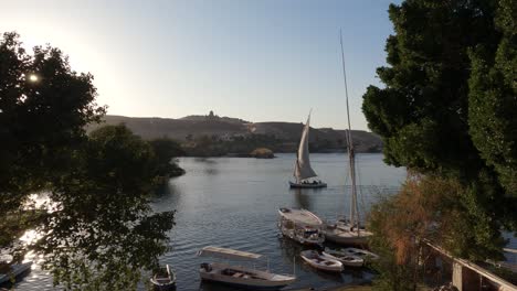 view from bank of river nile, sailboat sailing slowly on the river, elephantine island, aswan