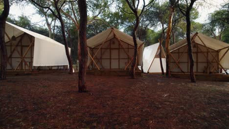 backward-drone-footage-flying-out-of-one-of-the-white-tents-of-a-campsite-in-Huelva,-Spain