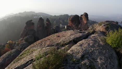 slow reveal of the town and residences beyond the big boulders of the sculptural rock formations of belogradchik in the province of vidin in northwestern bulgaria