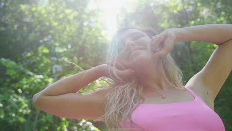 fun young blonde woman in bikini poses for the camera in a forest setting