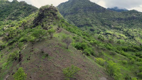 Drone-flying-along-the-ridge-of-a-mountain-range-with-green-vegetation-on-the-slopes