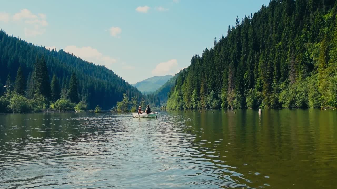 Familjepaddling med kanot på en flod mellan berg.