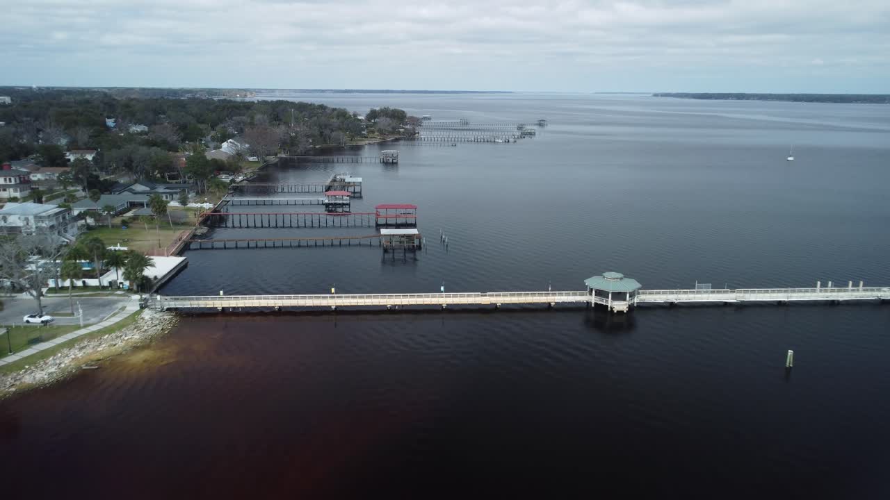 A stunning drone shot glides over the river, soaring above docks and sailboats, capturing the beauty of waterfront life.