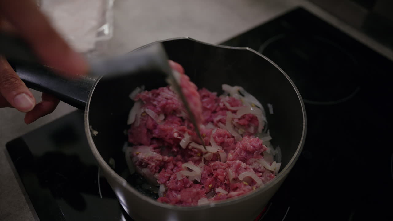 Close-up shot of hands mixing ground turkey with onion in a pot on the stove, minced meat, halal food, healthy eating, cooking lunch, dinner, protein rich diet, fitness meal plan, fresh ingredient