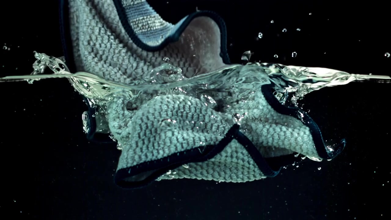 Mikrofiberklud, der sænkes ned i klart vand i slowmotion