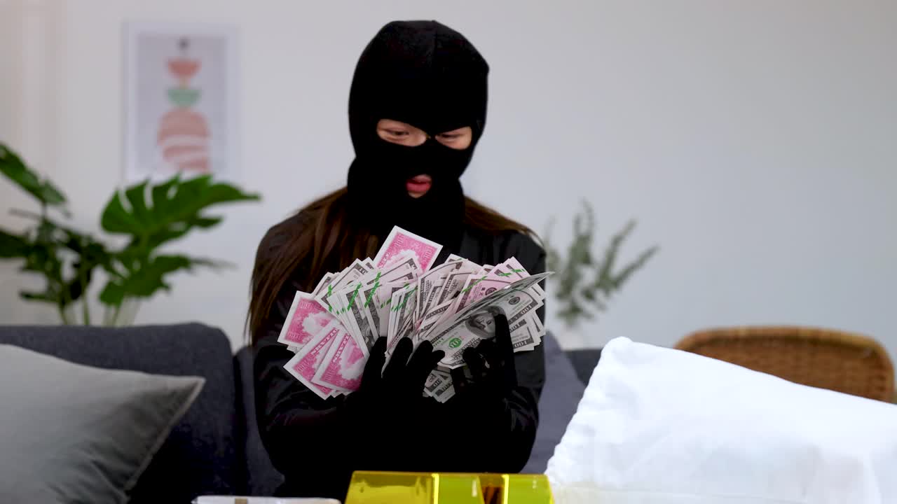 Un criminale mascherato conta una grossa pila di soldi seduto vicino a lingotti d'oro al chiuso