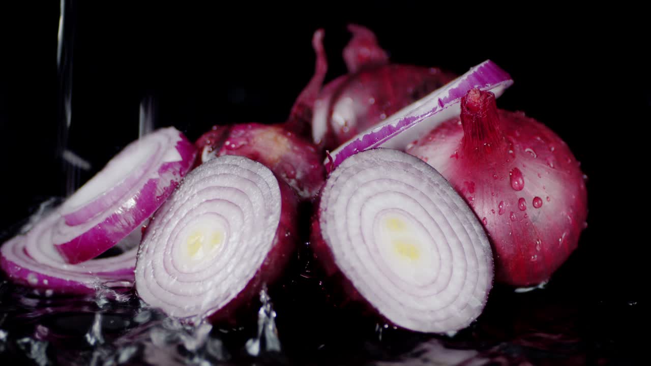 Sliced red onion on falling water drops.