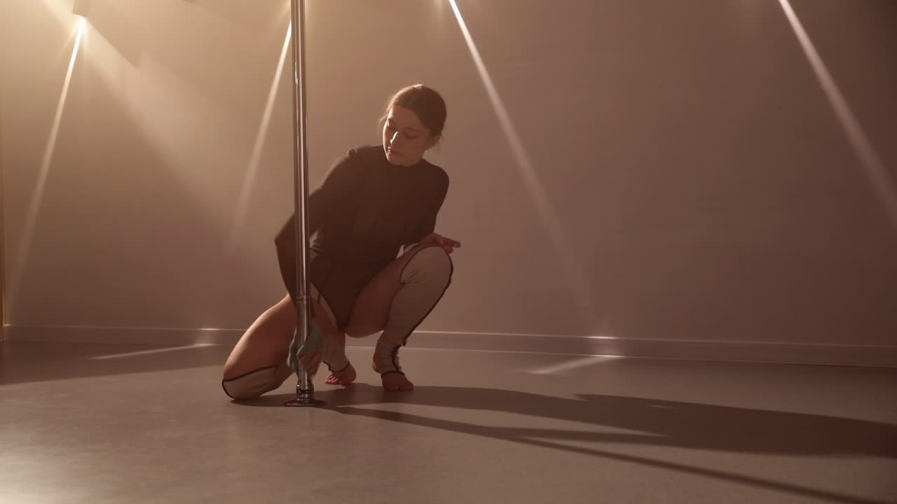 Girl cleaning the pole dance bar with a cloth in a studio