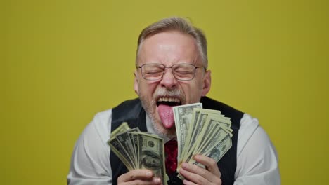 Businessman isolated on yellow. Handsome mature businessman with money isolated over background
