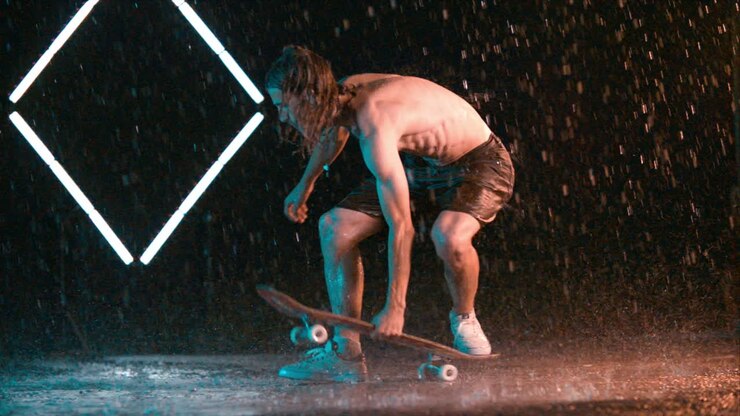 Incredibile acrobazia di spinning con lo skateboard di un uomo, con effetto pioggia bagnata in studio.