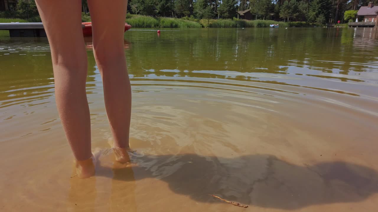 jovencita descalza en aguas poco profundas a un lado del lago en verano