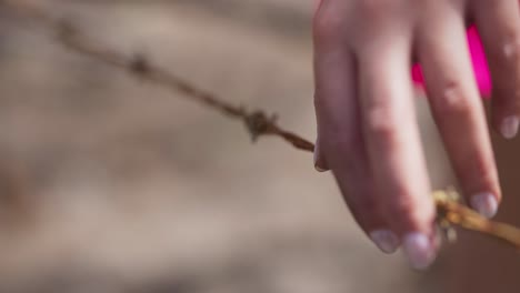 manos femeninas tocando el alambre de púas