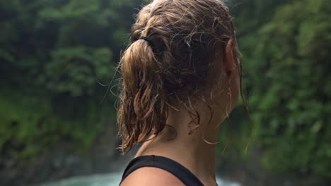 woman looking towards a rio celeste waterfall in the blurred background.the serene scene captures a moment of quiet contemplation for the raw beauty of nature at rio celeste