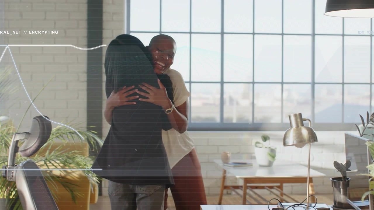 Two women coworkers having handshake-then-hug in office, graphic overlays over desk during greeting