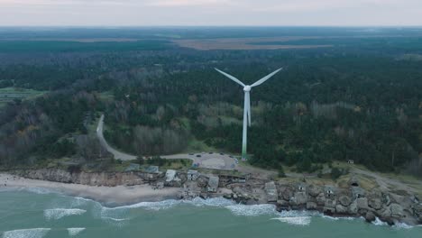 establishing aerial view of abandoned seaside fortification buildings at karosta northern forts on the beach of baltic sea in liepaja, overcast day, wind turbine, drone shot moving forward, tilt down