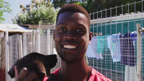 hombre voluntario afroamericano en un refugio para perros con un cachorro