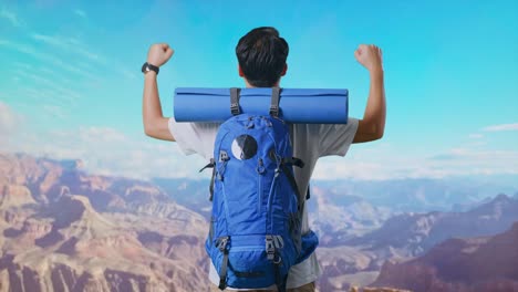 back view of a male hiker with mountaineering backpack screaming goal celebrating the success while traveling at the top of mountain