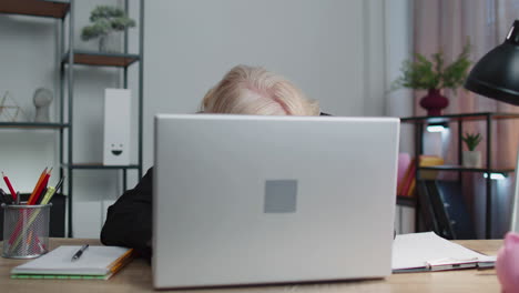 Senior mature older business woman hiding behind laptop computer, making funny face, fooling around