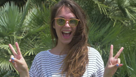 happy young woman with sunglasses giving peace sign