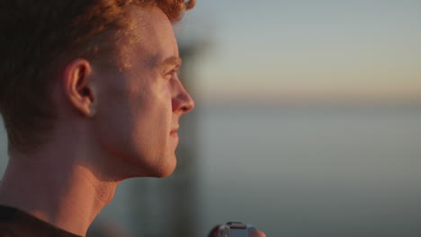 Close up profile of young male photographer taking outdoor photo at sunset