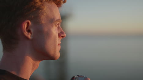 close up profile of young male photographer taking outdoor photo at sunset