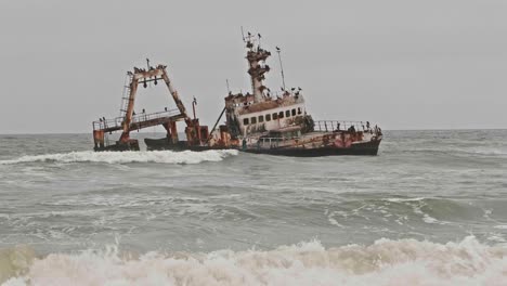 waves rolling in past zeila shipwreck along namibia skeleton coast, wide shot