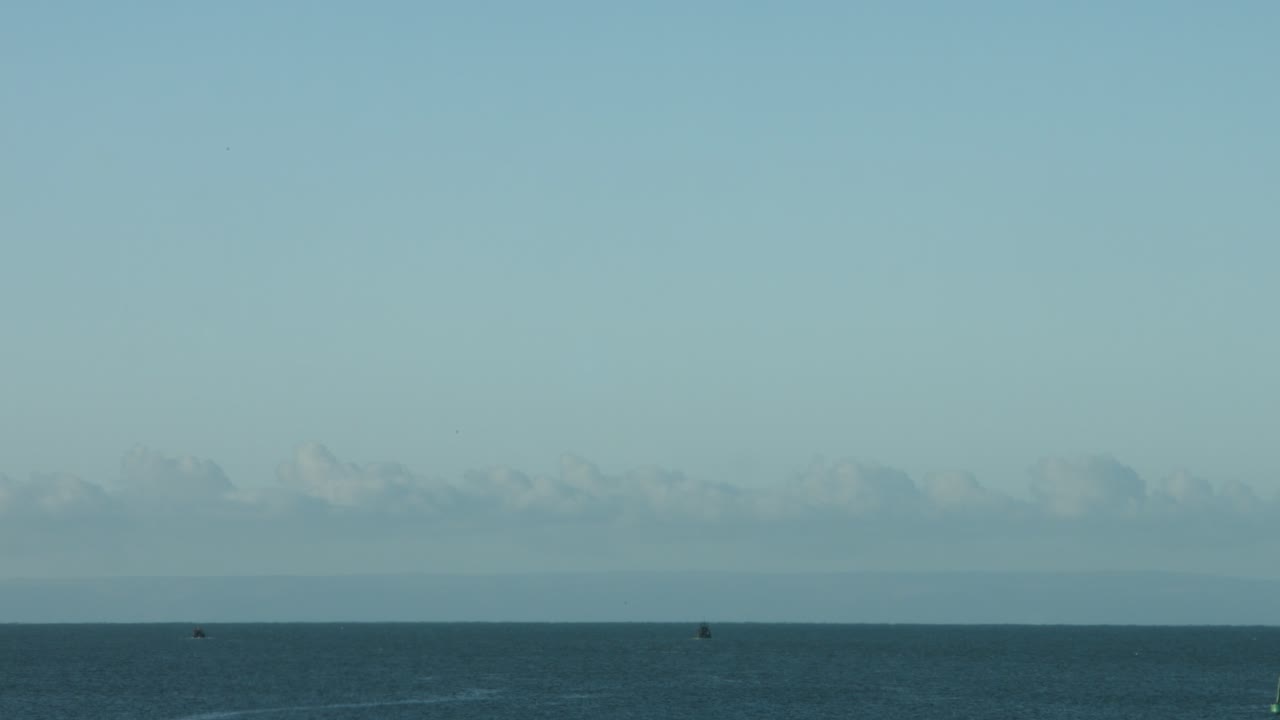 4k 거리에 데본 해안선이 있는 스완지 영국에서 일출 시 바다로 향하는 두 척의 어선의 시간 경과